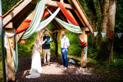 a couple and their celebrant under the oak arbour at the woods at oakley