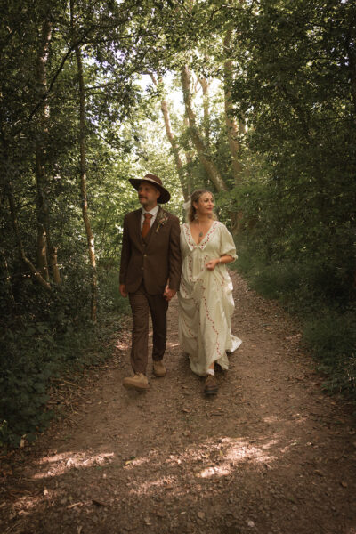 a bride and groom walk through the woods at oakley