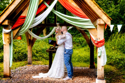 a couple kiss under an oak arbour in a woodland 