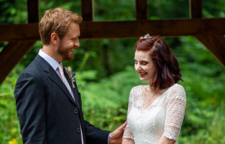 a bride and groom laugh under an oak arbour in a woodland