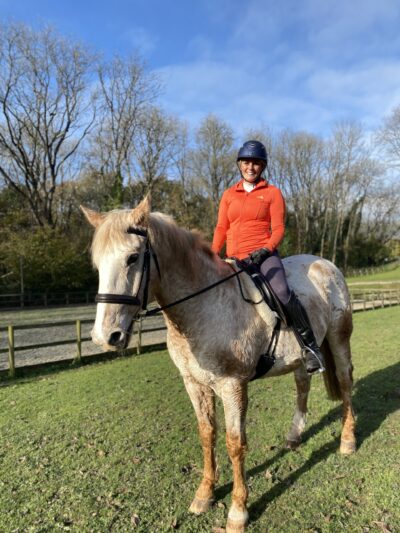 a woman smiling and sitting on a horse 