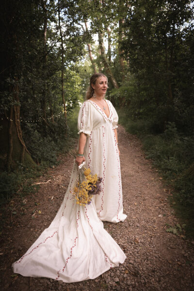 a bride stands in her wedding dress in the forest at the Woods at Oakley carrying her bouquet