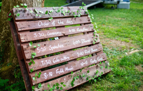 a painted pallet with ivy on with the order of the day drawn on, leaning against a tree in a woodland