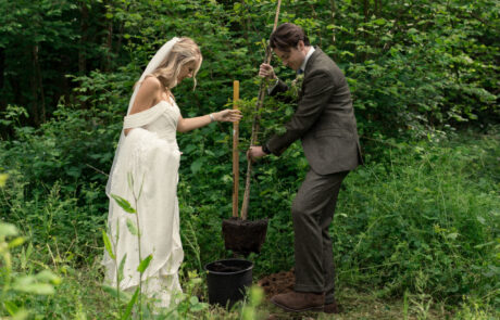 A bride and groom plant their wedding tree in a woodland.