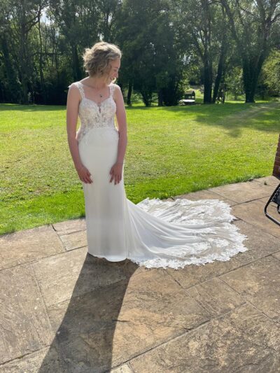 A bride stands in a garden at The Woods at Oakley looking down at her wedding dress