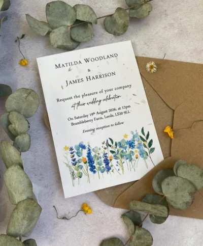 a woodland wedding seed paper invitation lying on an envelope and surrounded by plants