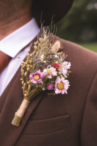 a wildflower buttonhole sits on a man's suit