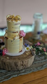 a cream wedding cake sitting on a wooden log slice decorated with flowers