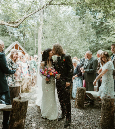 A bride and groom kiss as they walk down the aisle surrounding by their family