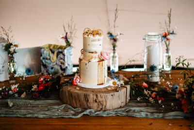 A white wedding cake on a log slice on a wooden table