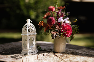 A small lantern and posy jar with flowers on a wooden tabletop