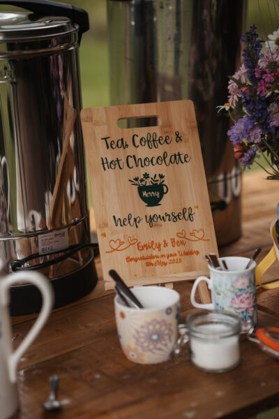 an urn, cups and hot chocolate sign on a wooden table