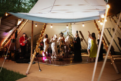 wedding guests dance under a tipi with fairy lights