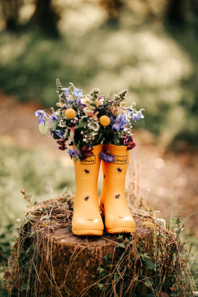 a pair of yellow wellies with flowers in them on a wooden stump